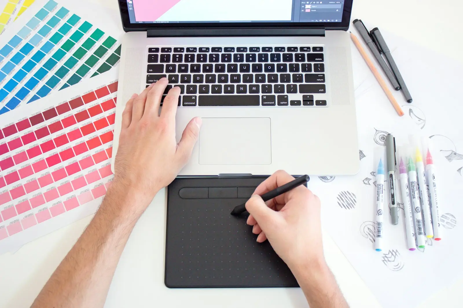Designer preparing a print-ready vector file with pen tablet and color swatches