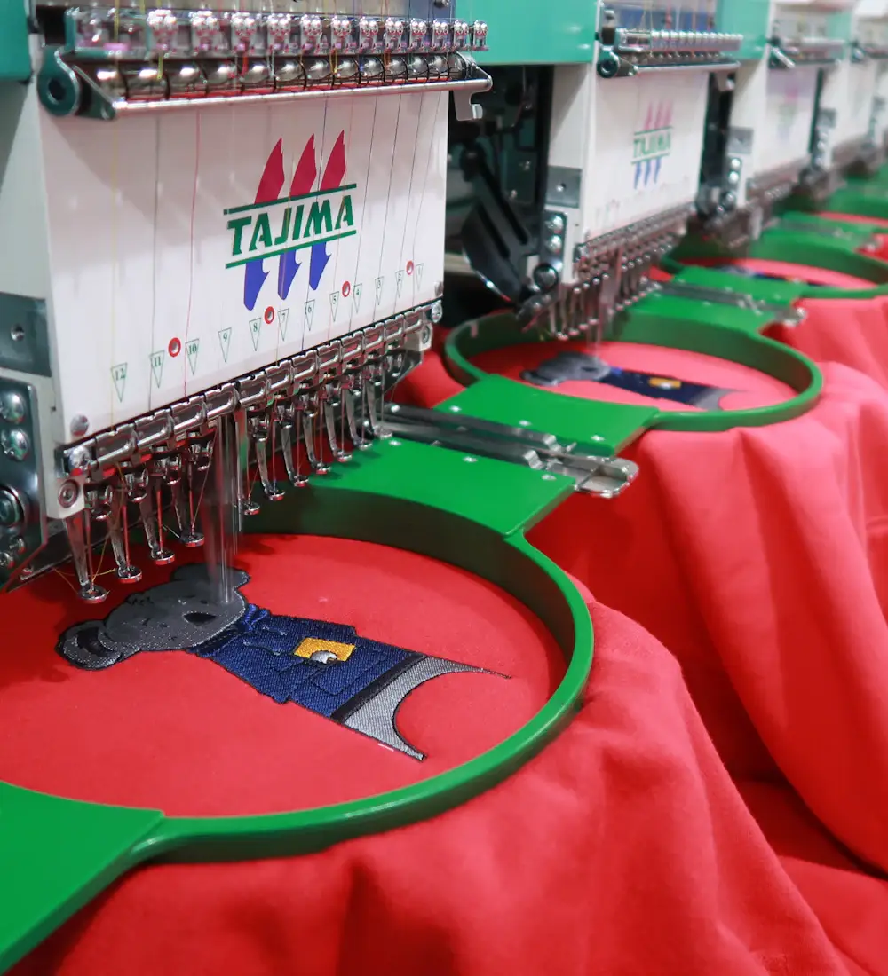 Multi-head embroidery machine stitching a logo from an embroidery vector file